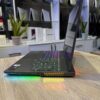 A sleek gaming laptop displayed at an electronics store, featuring a colorful backlit keyboard and various ports on the side.