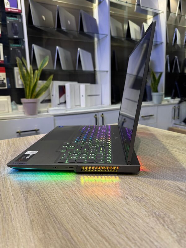 A sleek gaming laptop displayed at an electronics store, featuring a colorful backlit keyboard and various ports on the side.